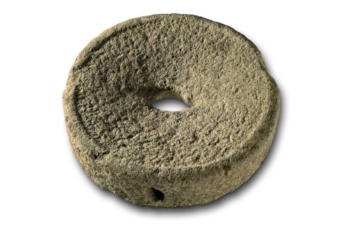 Läufer einer keltischen oder frührömischen Handmühle. In das Loch auf der Seitenfläche wurde ein hölzerner Hebel gesteckt. Dm: ca. 40 cm.
