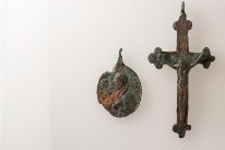 Bild des Medaillons und Kreuz, die erst bei der Konservierung getrennt werden konnten, da sie zusammenkorrodiert waren.
